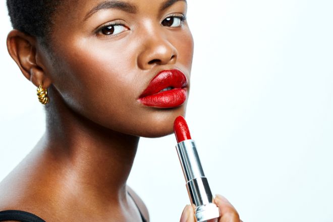 Beautiful African American model with red lips and gorgeous skin, posing and looking into camera. Advertising skincare and cosmetics for ethnic women. Showing the latest shade of a popular lipstick