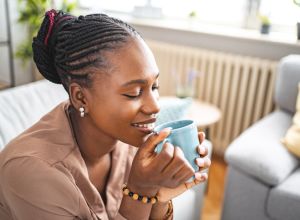 Black woman enjoying her freshly made coffee while relaxing in her living room