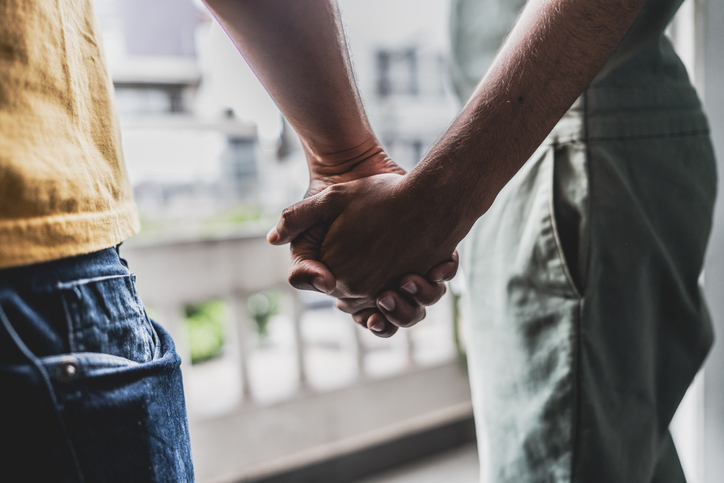 Gay couple holding hands at home