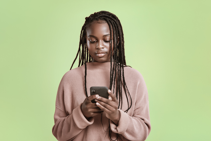 Beautiful teenager using smartphone on green background