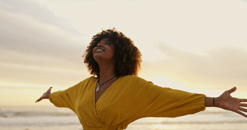 Sunrise, beach and happy woman for freedom, vacation and holiday weekend in Miami with smile. Ocean, mindfulness and carefree for adventure, peaceful and joy for sea breeze by scenic view outdoor