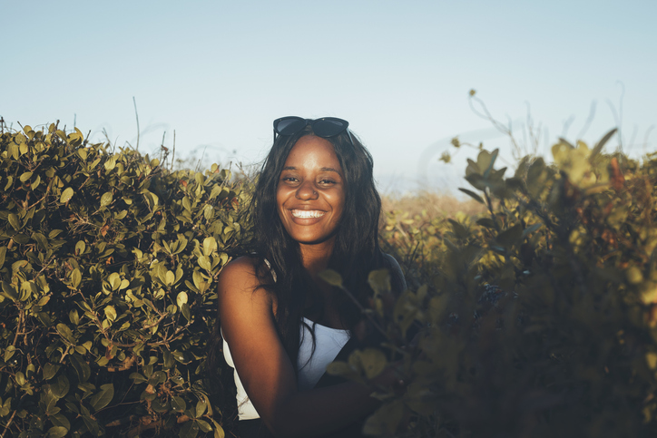 Portrait Of Cheerful Young Woman Standing Amidst Plants