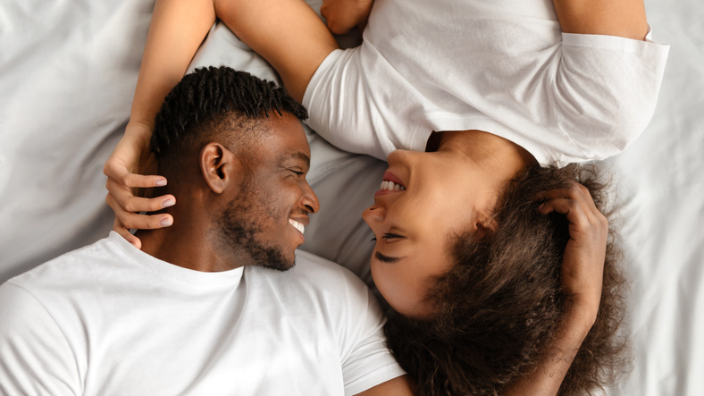 Loving young black spouses flirting enjoying intimacy in bed, panorama