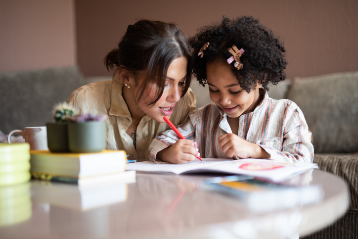 Happy mother and daughter coloring in the living room.