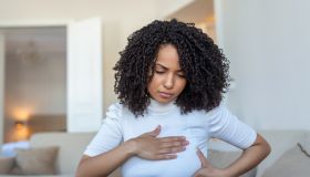Young African American woman palpating her breast by herself that she concern about breast cancer. Healthcare and breast cancer concept