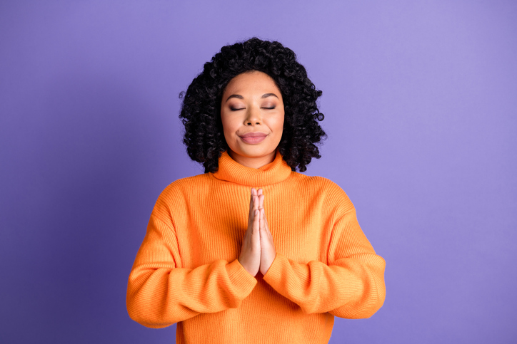 Photo of charming dreamy woman wear orange sweater arms together praying empty space isolated violet color background