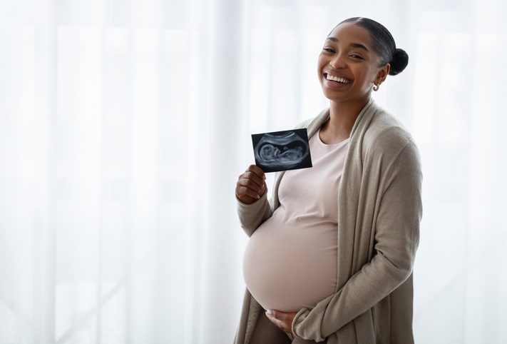 Happy Black Pregnant Lady Holding Ultrasound Photo Of Her Baby