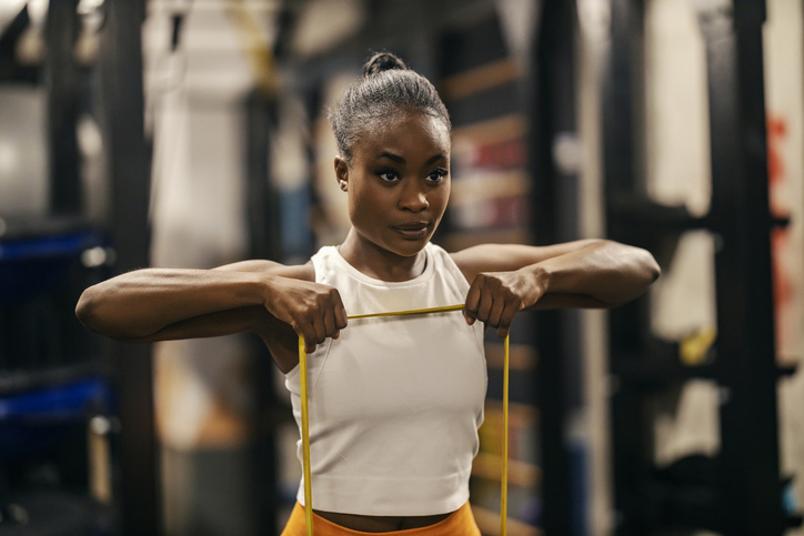Portrait of a fit black sportswoman stretching resistance band at the gym.