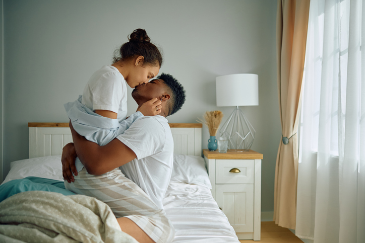 Affectionate multiracial couple kissing in bedroom.