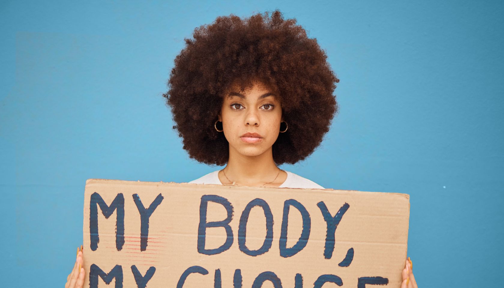 Protest, human rights and woman with a poster for abortion, body freedom and justice against a blue studio background. Choice, equality and portrait of an African girl with a board for a riot
