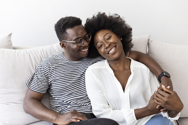 Happy Couple Embracing and Laughing on Comfortable Couch