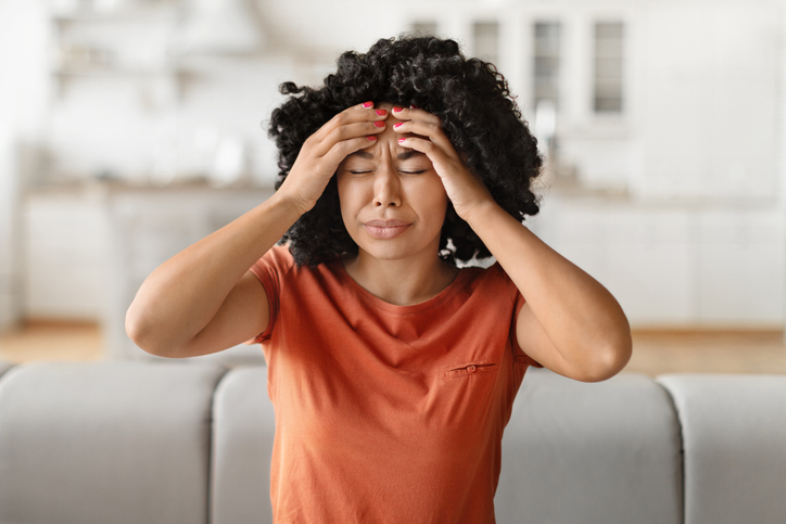 Headache Concept. Young black woman suffering from migraine at home