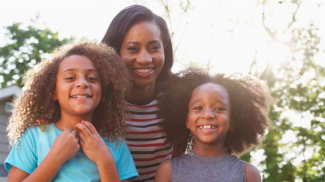 Portrait Of Smiling Mother And Children On Driveway At Home
