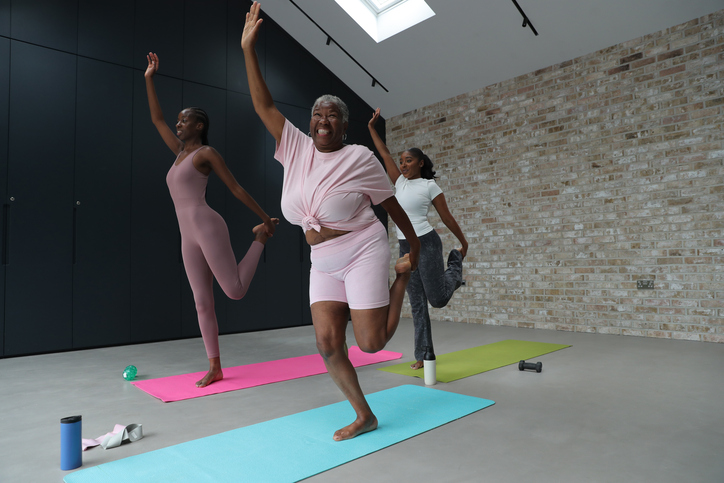 Women exercising in yoga studio: Three smiling women practicingÊNatarajasana exercise on yoga mats in yoga studio