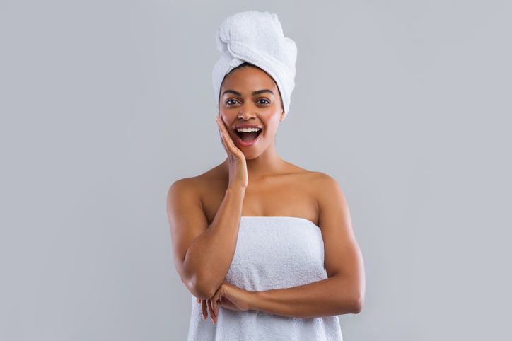 Excited woman wrapped in towels touching her cheek