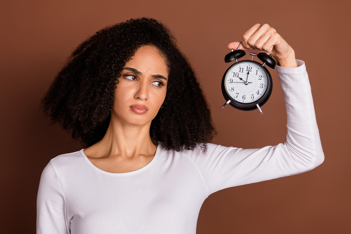 Portrait of nice young girl look alarm clock wear pullover isolated on brown color background