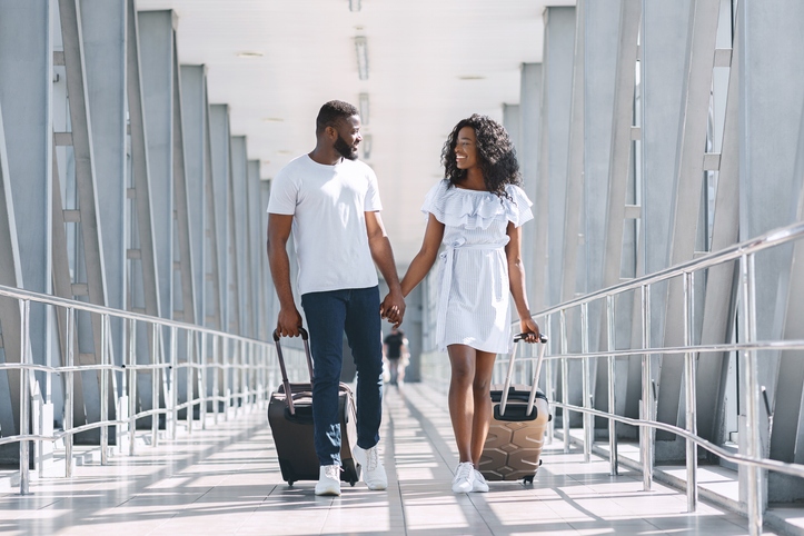 Black couple in love going on flight departure with suitcases