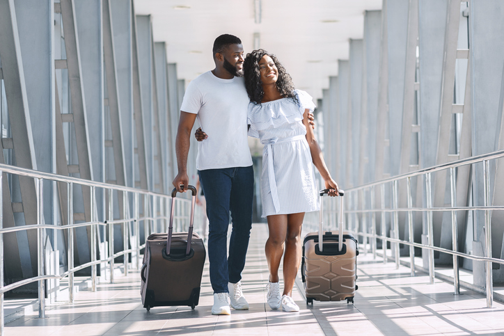 Loving black couple walking at covered passage in airport
