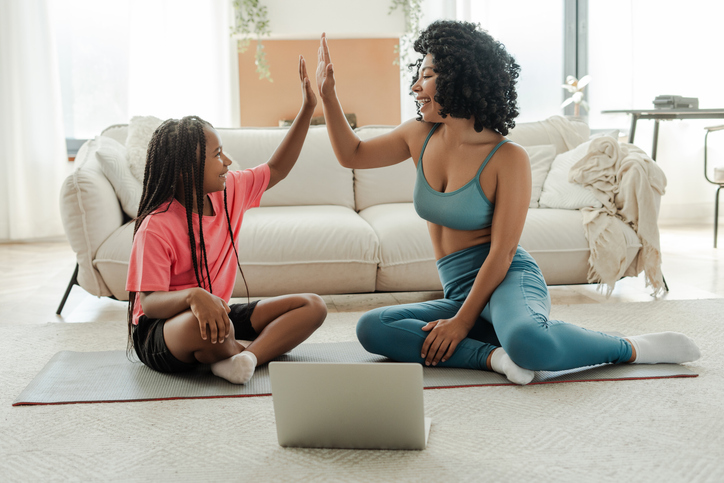 Mother and daughter giving high five after online workout at home