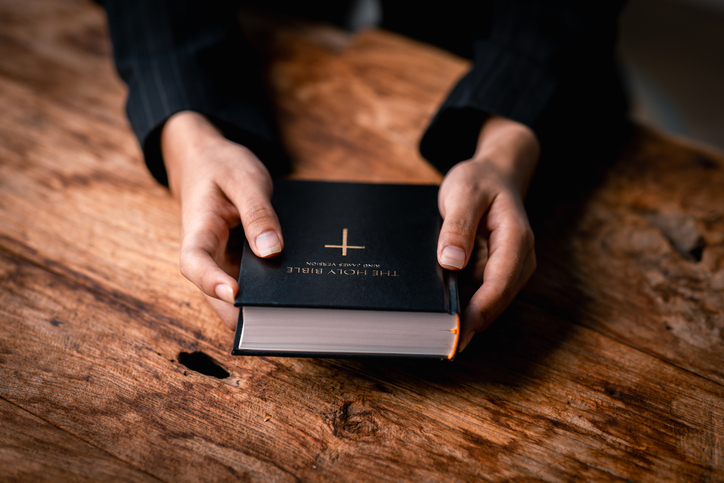 Hands folded in prayer on a Holy Bible in church concept for faith, spirituality and religion, woman praying on holy bible in the morning. woman hand with Bible praying.