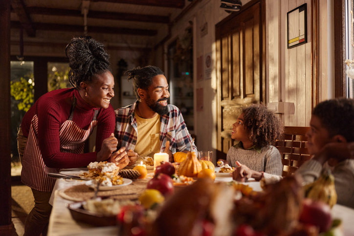 Happy African American family talking during snack time in dining room.