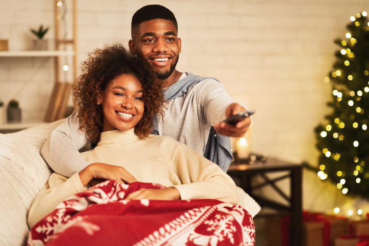 Afro couple in love at Christmas eve enjoy watching tv