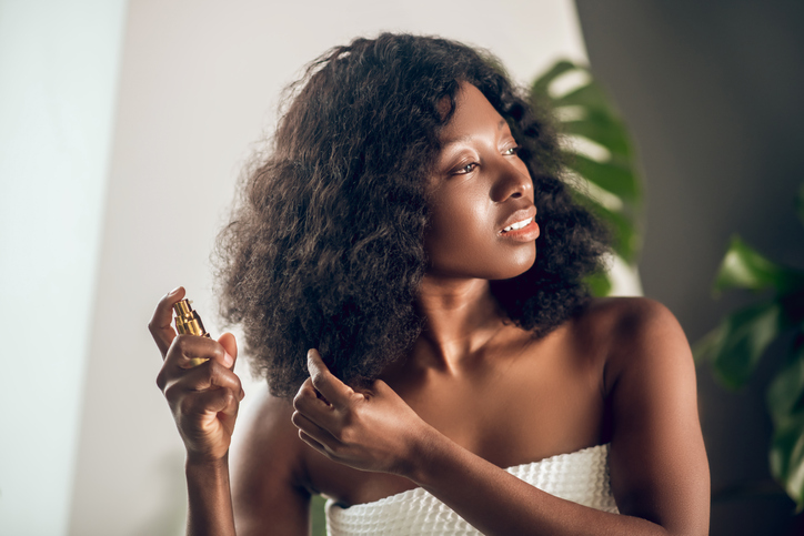 Appealing african american woman spraying serum on her hair