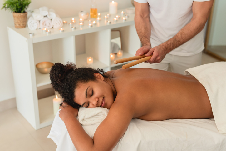 Spa therapist using singing bowls near a black lady