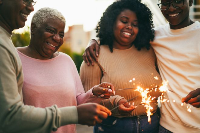 Happy african american family celebrating with sparklers winter holidays as Christmas and new years eve events - Family lifestyle and fest concept - Main focus on mother face