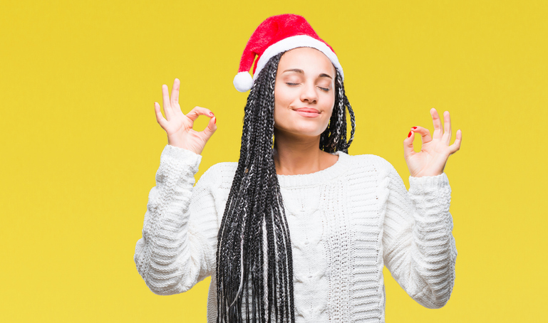 Young braided hair african american girl wearing christmas hat over isolated background relax and smiling with eyes closed doing meditation gesture with fingers. Yoga concept.