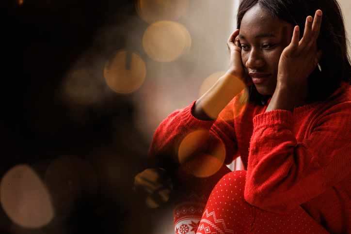 Portrait of young woman sitting on the window sill, looking outside, contemplating
