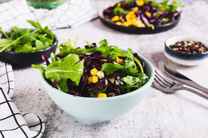 Red cabbage, corn and arugula salad in a bowl on the table