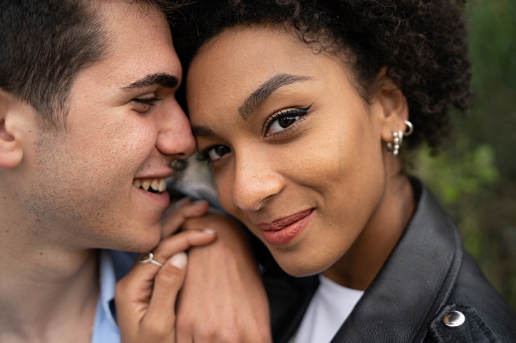 Closeup portrait of a biracial couple hugging outdoors - multi-ethnic couple in engaging moment - diverse people lifestyle concept