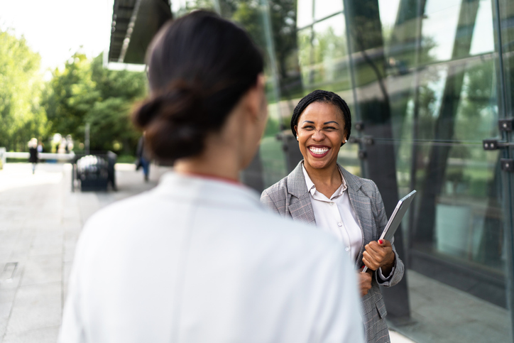 Two business women talking in front of their company