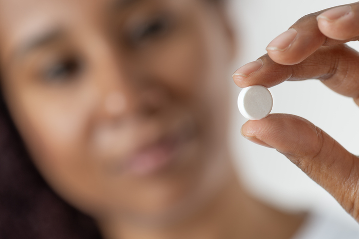 Close-up of a Pill Held Between Fingers