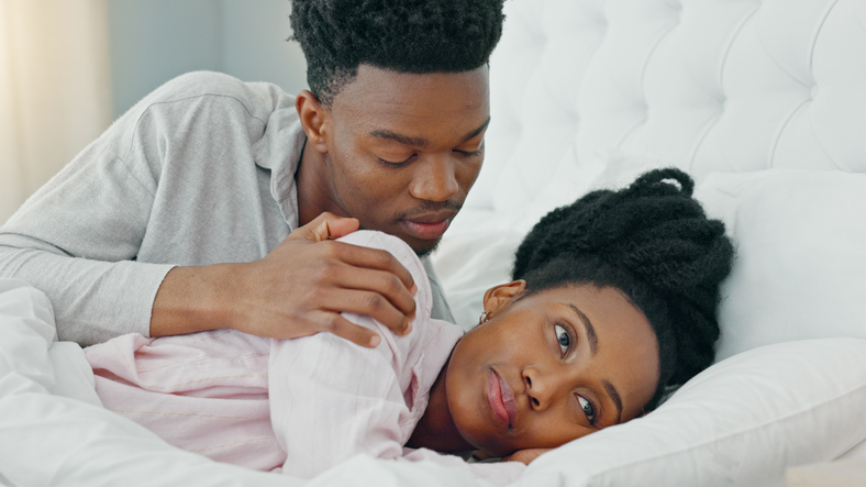 Angry, sorry or apology with a black couple in bed together in a home after a fight or argument. Divorce, breakup or marriage problems with a frustrated woman and man in the bedroom during conflict