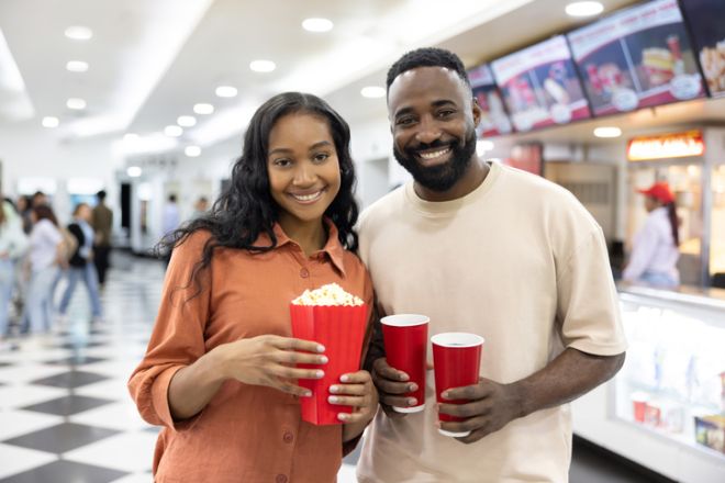 Portrait of a couple buying popcorn and drinks at the cinema