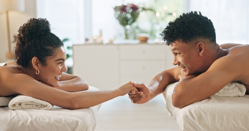 Spa, couple and happy with holding hands for back massage. luxury and bonding for valentines day. People, resort and smile in relationship on break for anniversary, body therapy and self care