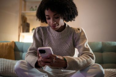 Young woman using smartphone at home on sofa