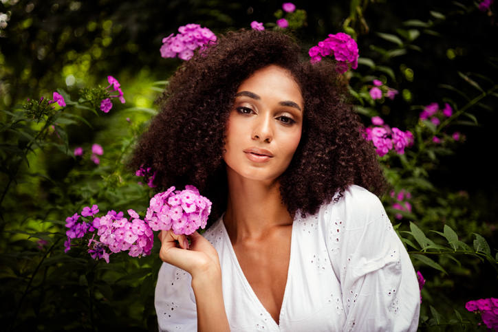 Photo of charming adorable cute girl dressed white stylish clothes hold blooming flowers in botanical garden outdoors