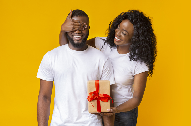 Pretty afro girl surprising her boyfriend with a gift