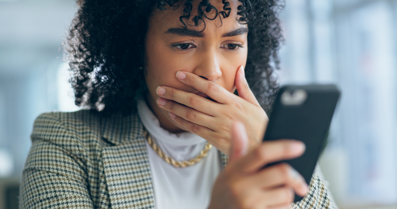 Business woman, reading phone and shocked for news, social media post or marketing error in office. Young african employee confused, surprise and stress on mobile for scam, mistake or wrong email