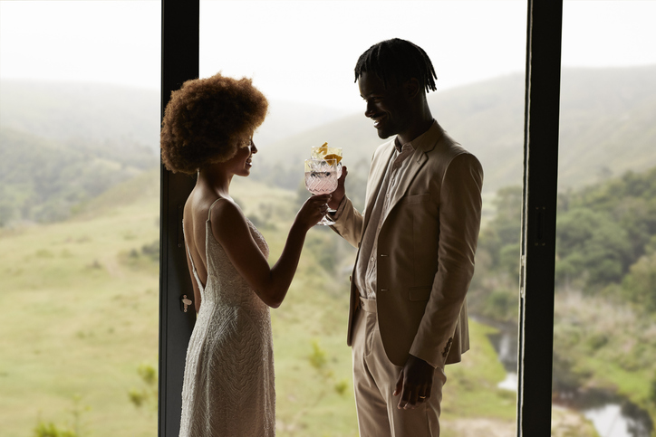 Happy married couple toasting drink by window