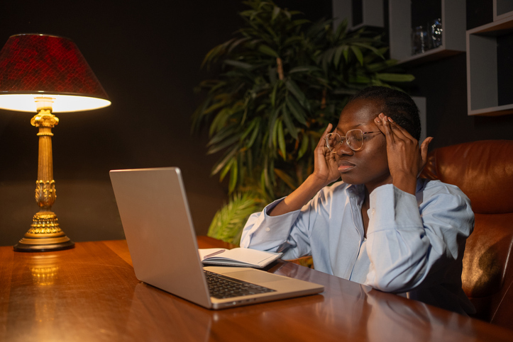 Stressed young manager suffering from headache while working late at night