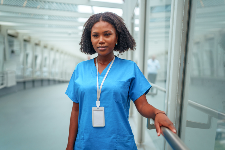 Female healthcare worker stands confidently outdoors, wearing medical scrubs