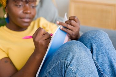 Young black woman writing in notebook at home