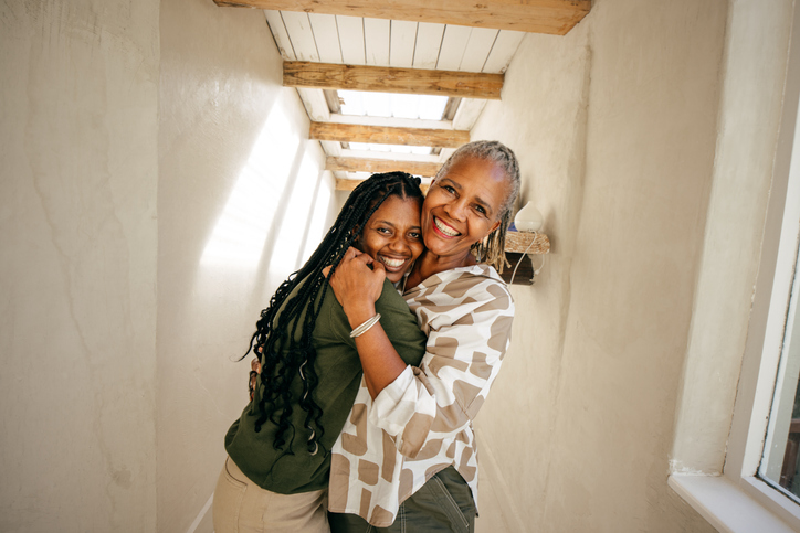 A mother and daughter share a warm hug, their smiles reflecting a deep bond and happiness.