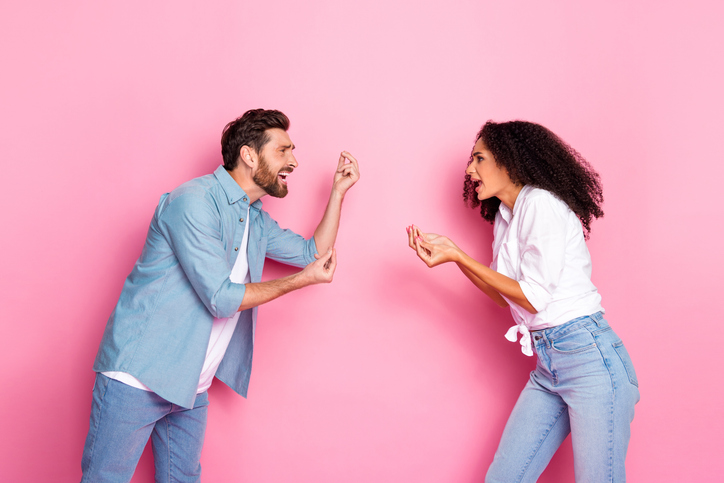 Young couple passionately arguing against pink backdrop representing emotions and diversity in relationships