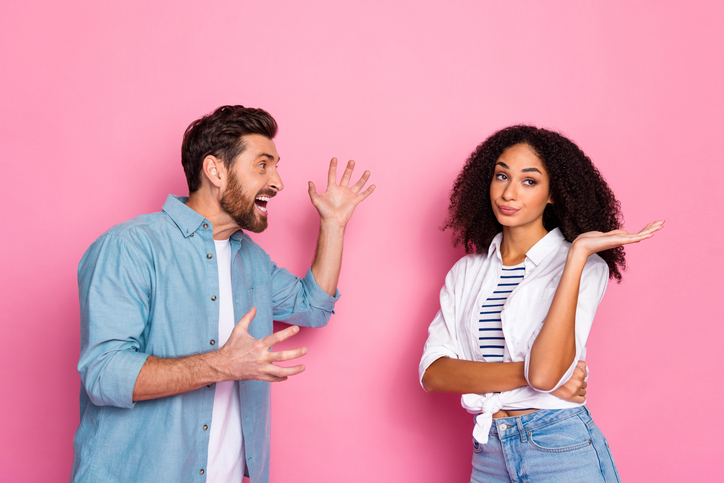 Young man and woman interacting humorously against a pink background with casual fashion