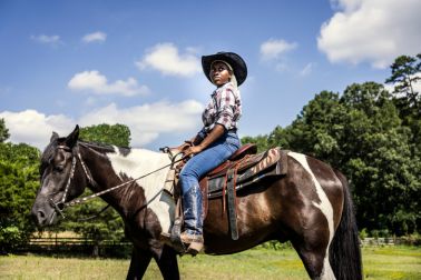 Young woman riding horse in pasture